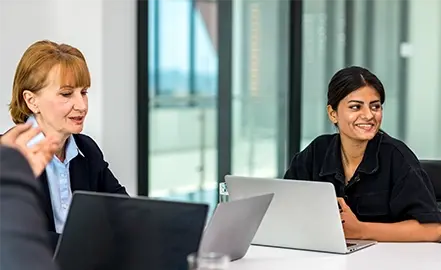 Image of two people behind a laptop talking